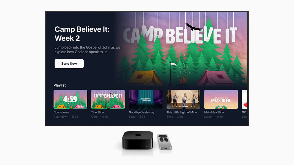 An Apple TV and its remote below a screen running Roomcaster — a kids ministry program with its playlist of countdown, songs, and lesson videos queued up